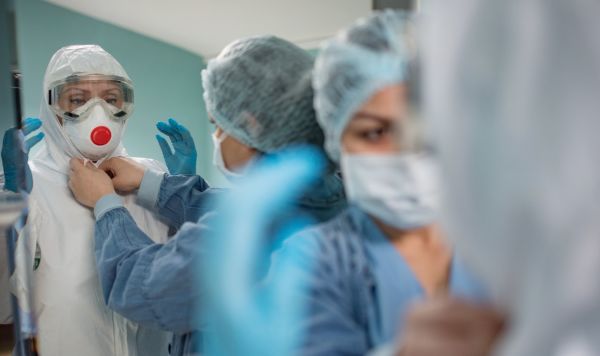 Медицинские работники надевают защитные костюмы и маски для работы с больными с коронавирусной инфекцией