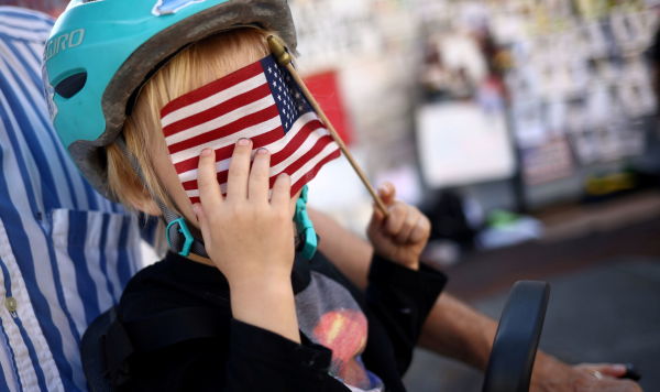 Ребенок закрывает лицо американским флагом