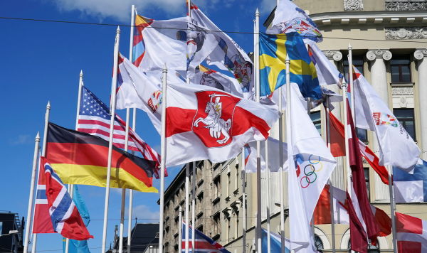 Бело-красно-белый флаг рядом с флагами стран-участниц чемпионата мира по хоккею с шайбой в Риге, Латвия, 24 мая 2021 года