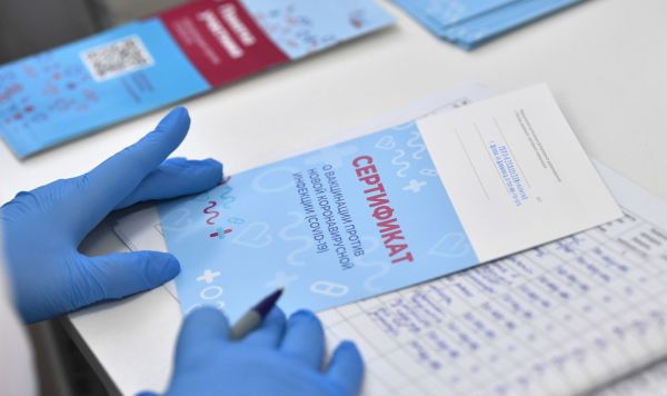 Медицинская сестра выписывает пациенту сертификат о вакцинации против коронавирусной инфекции 