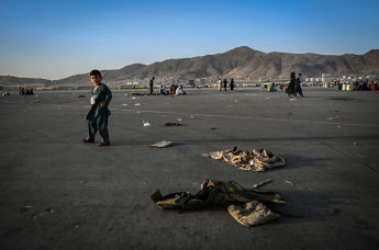 Ребенок около брошенной военной форме в аэропорту Кабула, 16 августа 2021