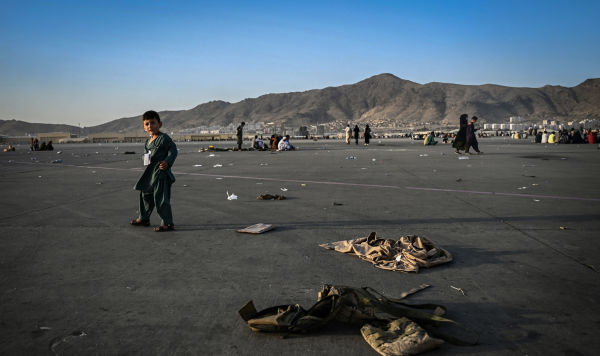 Ребенок около брошенной военной форме в аэропорту Кабула, 16 августа 2021