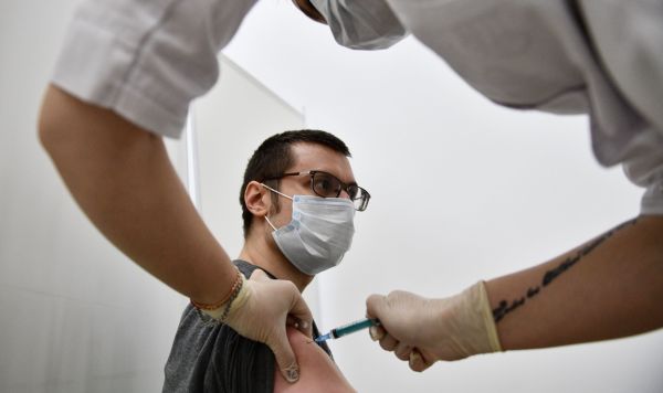 Мужчина во время вакцинации от COVID-19 и сезонного гриппа в прививочном пункте
