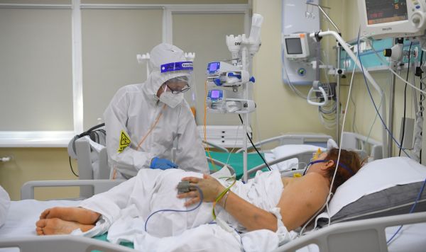 Медицинский работник у постели пациента в отделении реанимации и интенсивной терапии