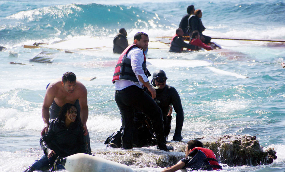 Местные жители помогаю беженцам выбраться на берег после крушения судна с мигрантами около острова Родос, Греция, 20 апреля 2015