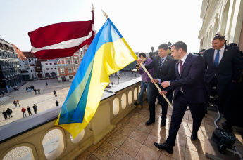 Мэр Риги Мартиньш Стакис, вице-мэр Эдвардс Смилтенс и посол Украины Александр Мищенко водружают флаги флаг Украины на здание Рижской думы