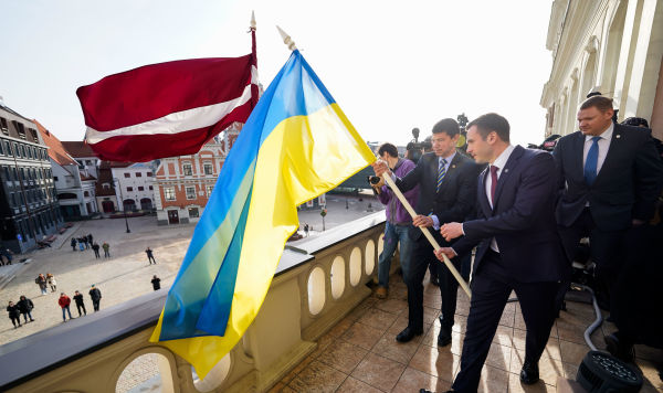 Мэр Риги Мартиньш Стакис, вице-мэр Эдвардс Смилтенс и посол Украины Александр Мищенко водружают флаги флаг Украины на здание Рижской думы