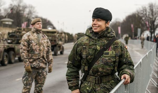 Военнослужащая из Испании фотографируется перед парадом в Риге в День независимости Латвии