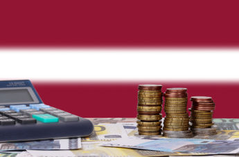 Монеты и купюры евро, калькулятор на фоне флага Латвии
