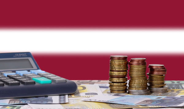Монеты и купюры евро, калькулятор на фоне флага Латвии