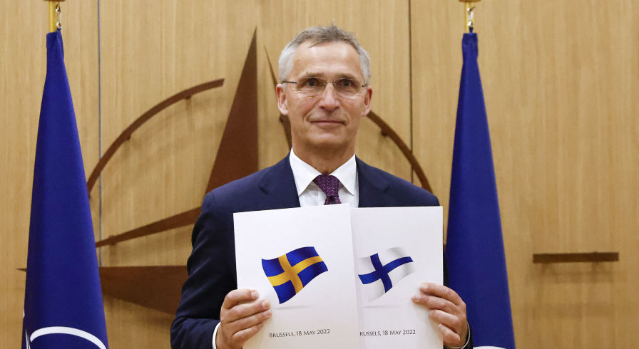 Генеральный секретарь НАТО Йенс Столтенберг позирует с заявочными документами по заявке Швеции и Финляндии на членство в НАТО, 18 мая 2022