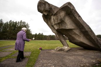 Женщина возлагает цветы к мемориалу памяти жертв фашизма, построенному на месте концентрационного лагеря "Саласпилс" ("Куртенгоф") в Латвии