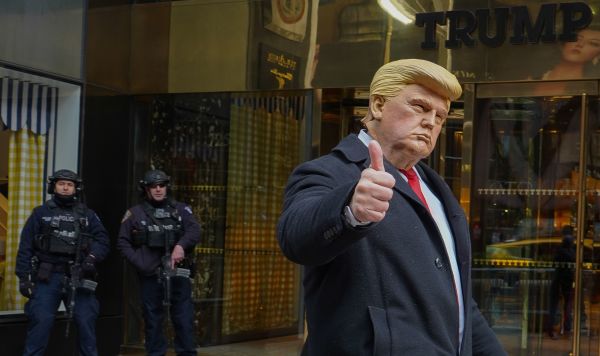 Мужчина в маске президента США Дональда Трампа у входа в башню Трампа в Нью-Йорке