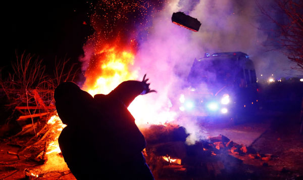 Демонстрант бросает камень в сторону полицейского фургона во время акции протеста против прибытия самолета с эвакуированными из китайской провинции Хубэй в село Новые Санжары, Украина, 20 февраля 2020