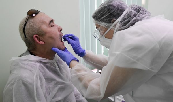 Сотрудник лаборатории проводит у пациента тест на коронавирус 