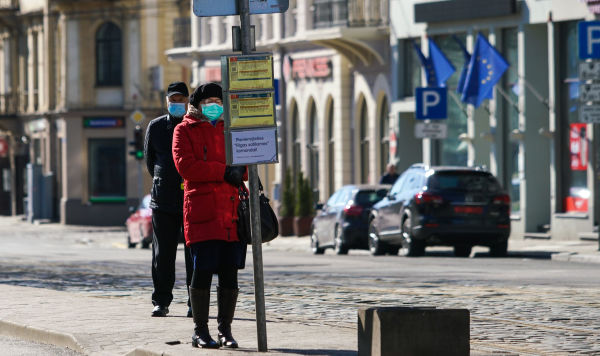 Женщина и мужчина в защитных масках на остановке общественного транспорта в Риге