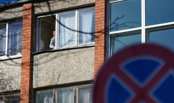 Мужчина смотрит из окна дома