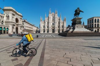 Курьер службы доставки на площади Пьяцца-дель-Дуомо в Милане