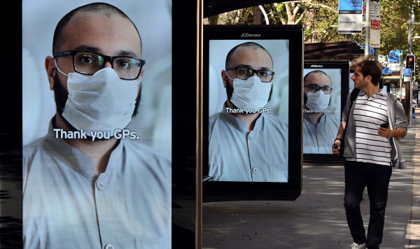 Мужчина проходит мимо рекламных щитов автобусной остановки, на которых изображены благодарственные послания медицинским работникам в ответ на вспышку коронавируса COVID-19 в Сиднее, 15 апреля 2020 года