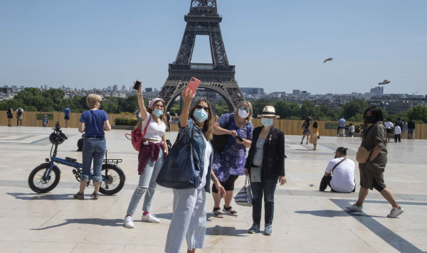 Люди делают селфи на фоне Эйфелевой башни в Париже, 17 мая 2020 года