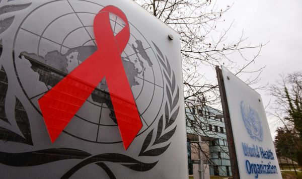 Эмблемы Всемирной организации здравоохранения и Объединённой программы ООН по ВИЧ/СПИД (ЮНЭЙДС) на входе в здание штаб-квартиры организации в Женеве
