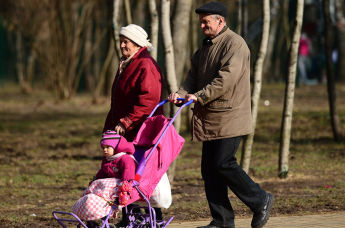 Пожилые люди гуляют с ребенком в парке.