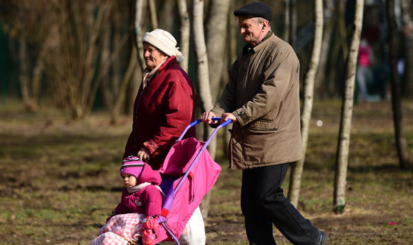 Пожилые люди гуляют с ребенком в парке.