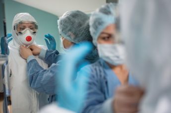 Медицинские работники надевают защитные костюмы и маски для работы с больными с коронавирусной инфекцией