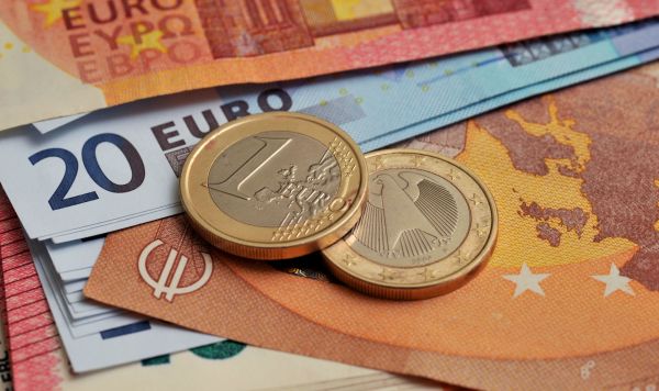 Монеты номиналом 1 евро на фоне банкнот номиналом 10 и 20 евро