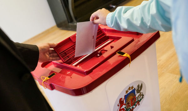 Избиратель опускает в урну конверт с бюллетенем