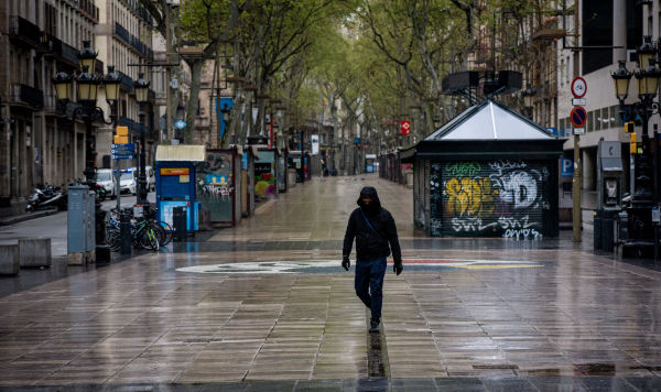 Мужчина в защитной маске идет по пустой пешеходной улице Раламбас в центре Барселоны