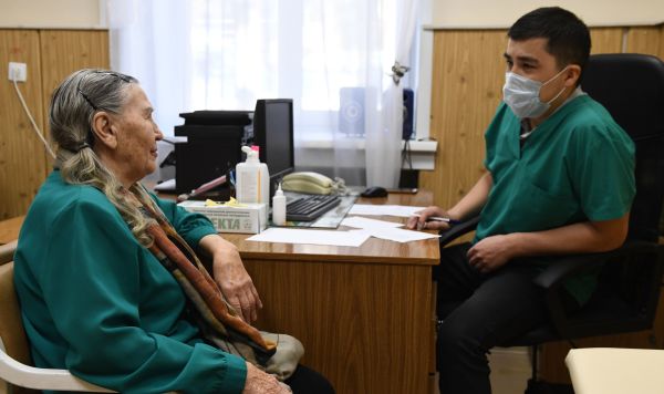 Врач проводит прием пациента в рамках выездной диспансеризации пожилых граждан
