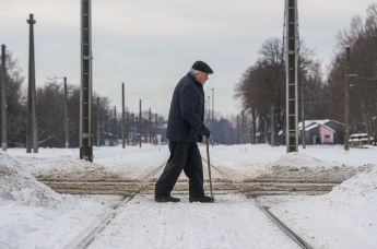 Пожилой мужчина переходит через железнодорожные пути