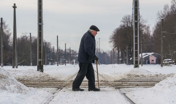 Пожилой мужчина переходит через железнодорожные пути
