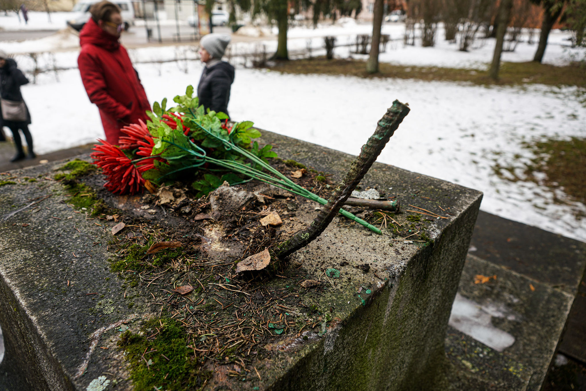 Мужчина и женщина у разрушенного памятника-пушки в парке по улице Ригас, установленного на братской могиле в Екабпилсе, 24 февраля 2021