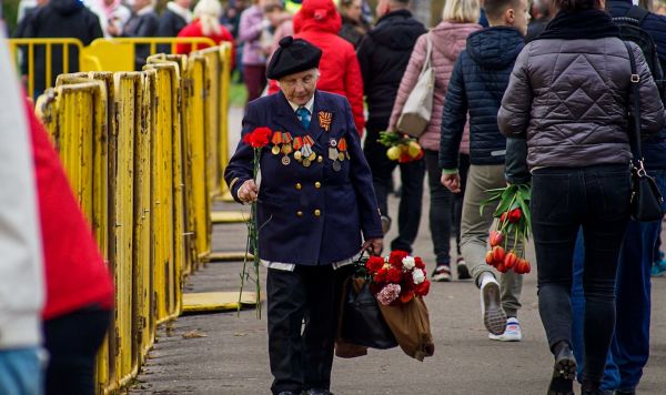 Люди идут, чтобы возложить цветы к памятнику Освободителям Риги