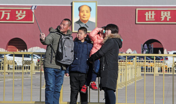 Семья фотографируется у портрета Мао Цзэдуна на центральной площади Пекина - Тяньаньмэнь ("Ворота небесного спокойствия")