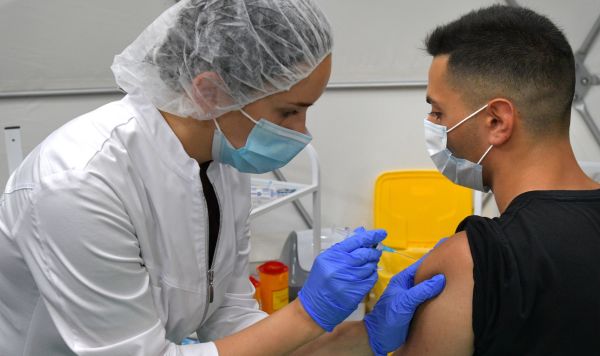 Медицинская сестра делает посетителю прививку в пункте вакцинации от Covid-19