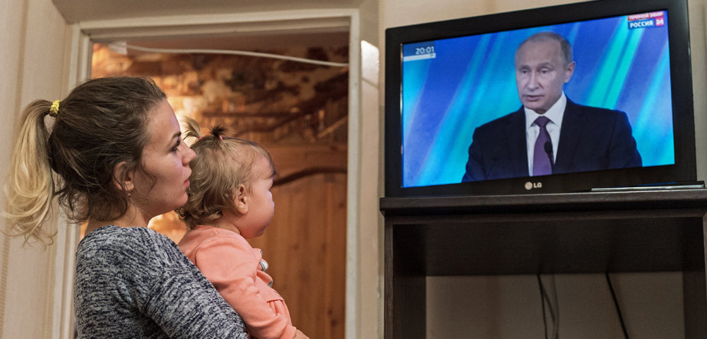 Женщина смотрит трансляцию выступления президента РФ Владимира Путина.