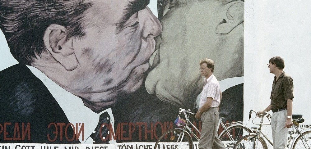 Жители Берлина рассматривают оставленный не разрушенным участок берлинской стены, расписанный художником.