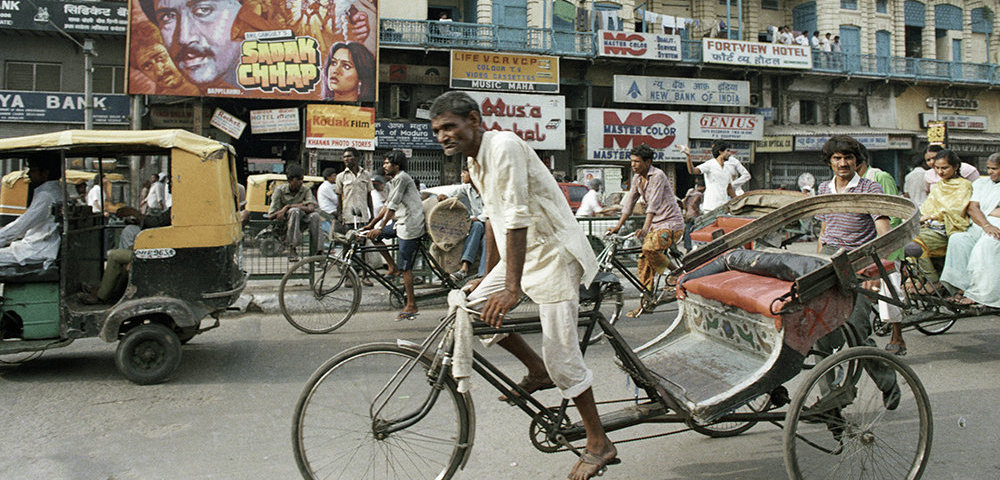 Велорикша едет по улице города Дели.