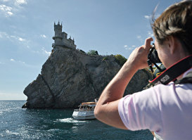 Турист фотографирует замок "Ласточкино гнездо" в Крыму