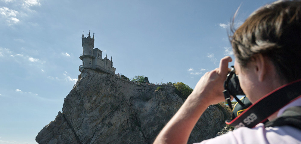 Турист фотографирует замок "Ласточкино гнездо" в Крыму