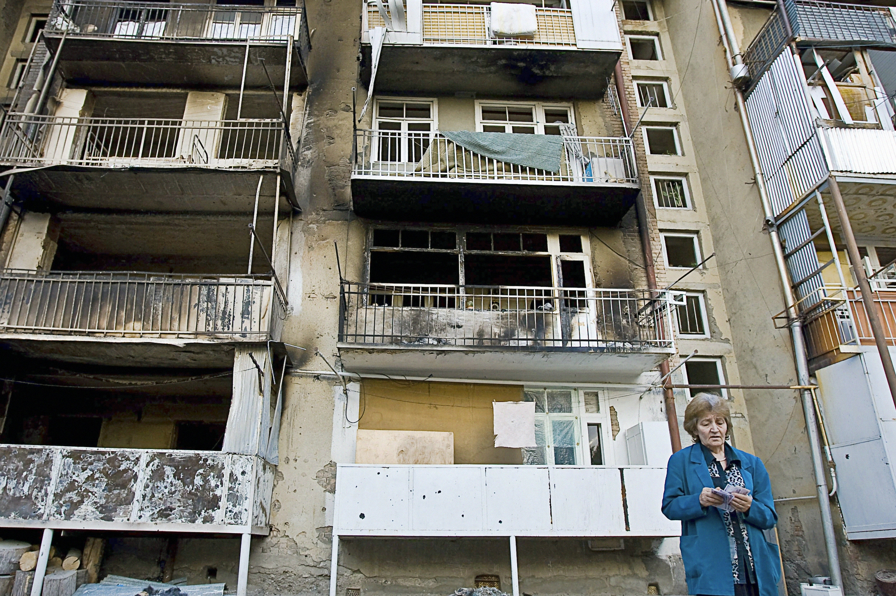 Жительница Цхинвали возле своего дома, пострадавшего от пуль и снарядов в ходе обстрелов города, 14 августа 2008