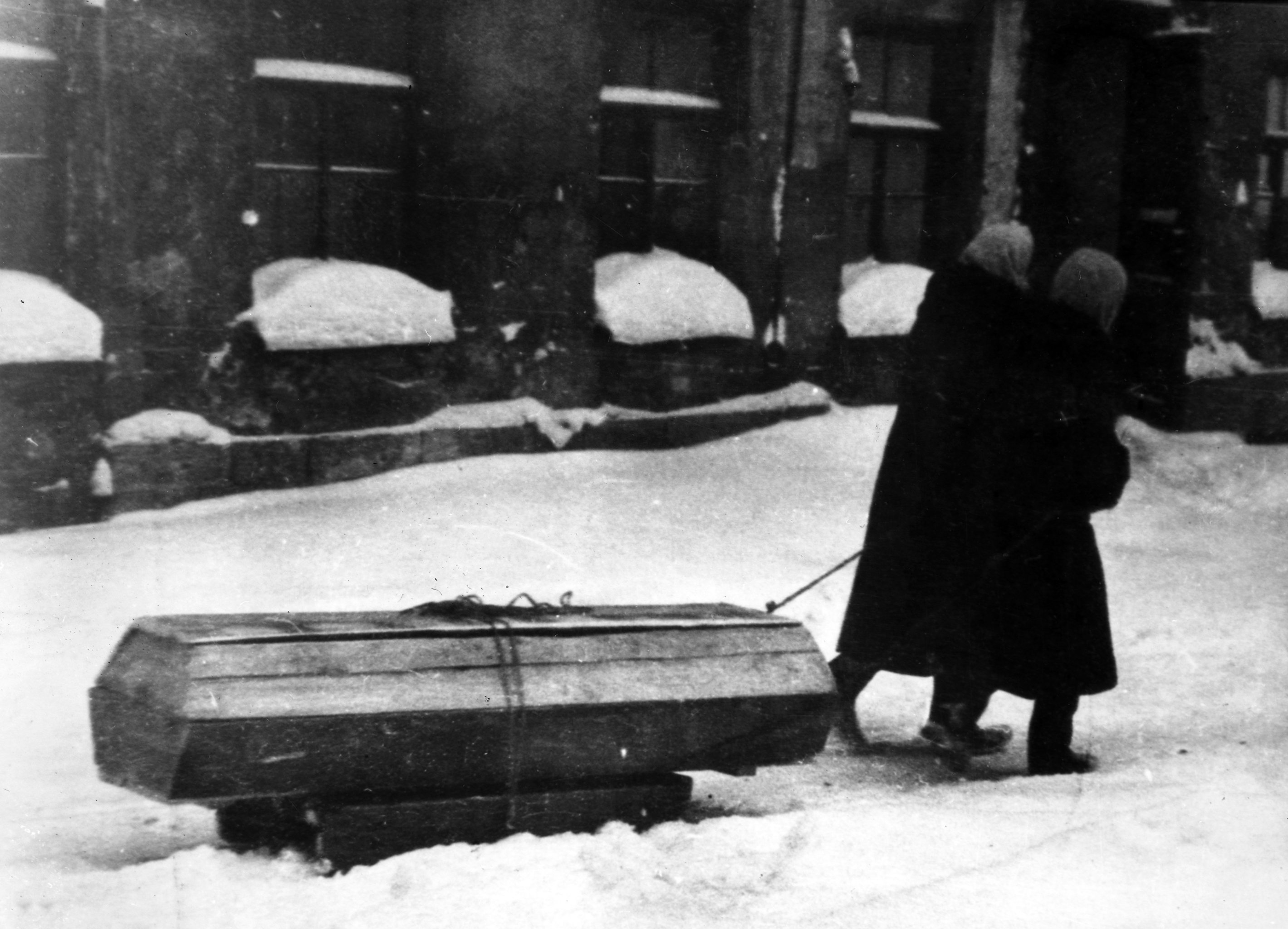 Жители блокадного Ленинграда везут на санках гроб с умершим.