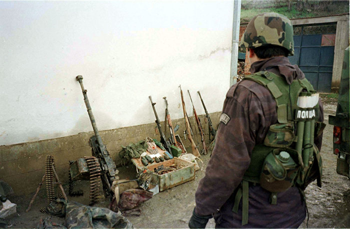 Сербский полицейский осматривает конфискованное оружие Армии освобождения Косово, деревня Рачак, 15 января 1999