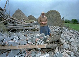 Пожилая женщина осматривает обломки своего дома, разрушенного в результате воздушных ударов НАТО