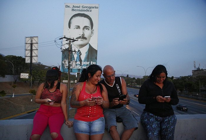 Отключение электричества и воды в Каракасе. Люди пытаются поймать сигнал мобильной связи на хайвее в Каракасе.