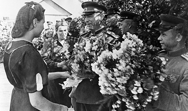 Освобожденные жители латышской деревни преподносят цветы члену Военного Совета II Прибалтийского фронта генерал-лейтенанту Владимиру Николаевичу Богаткину.