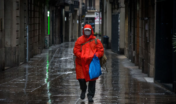 Мужчина в защитной маске идет по улице в центре Барселоны